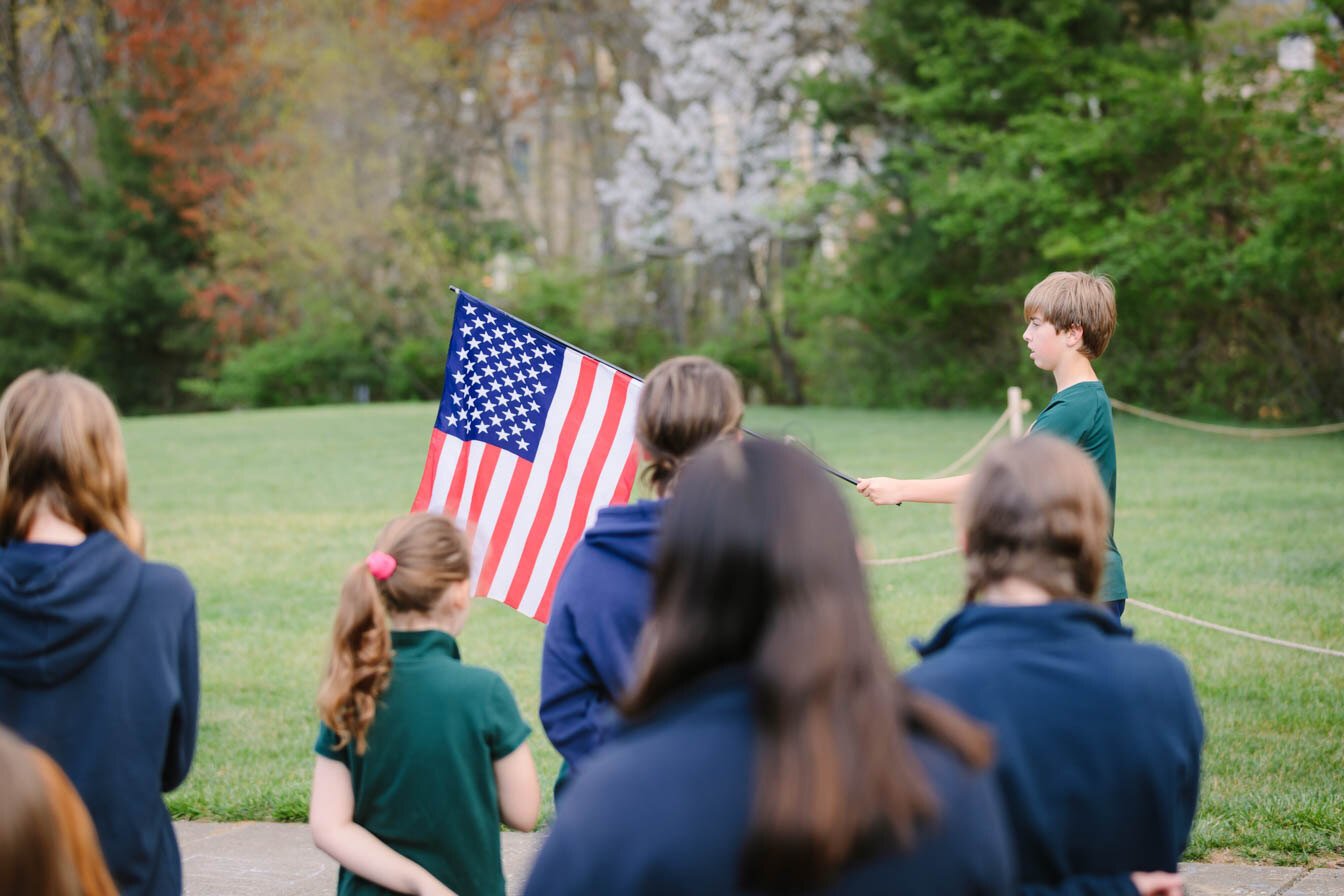 student raising flag at opening prayer